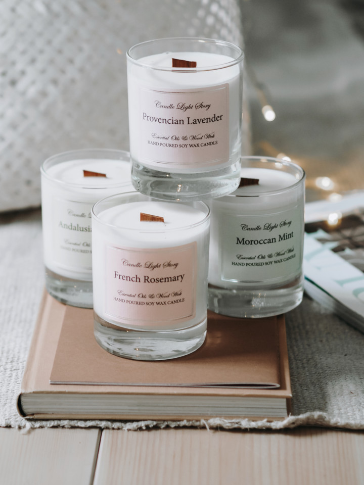 Neljä eri tuoksuista Candle Light Story Essentials kynttilää jotka ovat lasissa ja joiden päretyyppinen puusydän palaa lempeästi rätisten.
